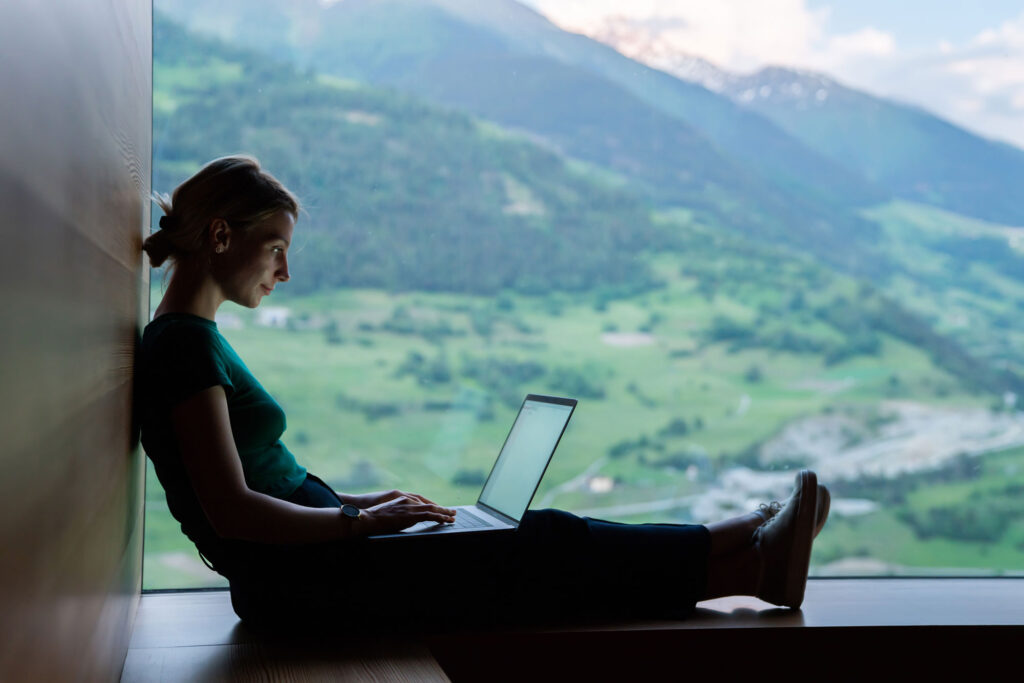 ragazza che lavora al PC davanti alle montagne